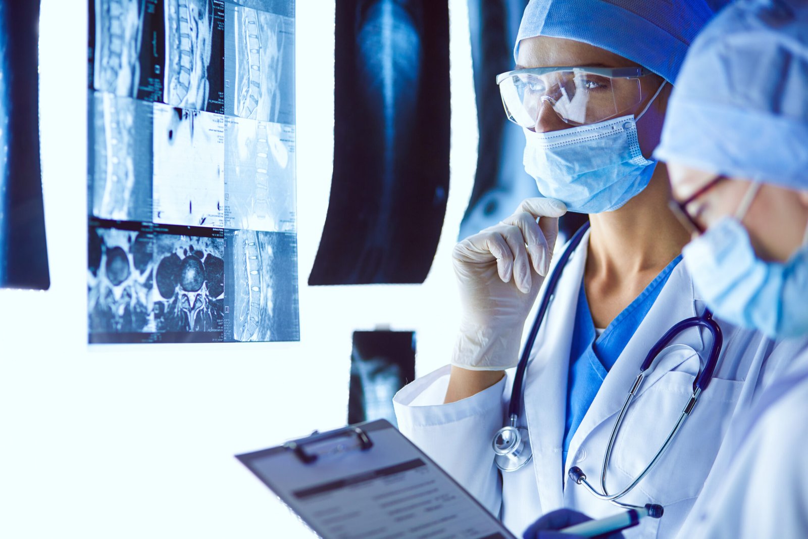 Fotografia de dois médicos de coluna examinando alguns exames.