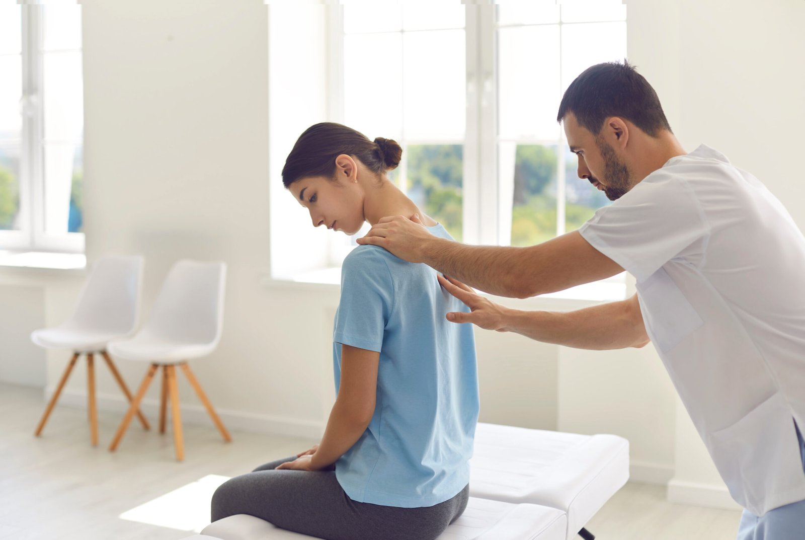 Fotografia de fisioterapeuta massageando as costas da paciente, que possui dores como a de discopatia degenerativa.