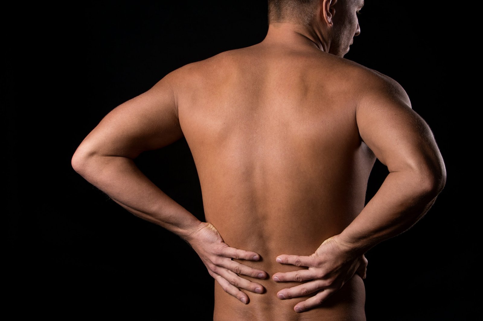 Fotografia de homem com mãos nas costas, indicando a dor da artrose na coluna