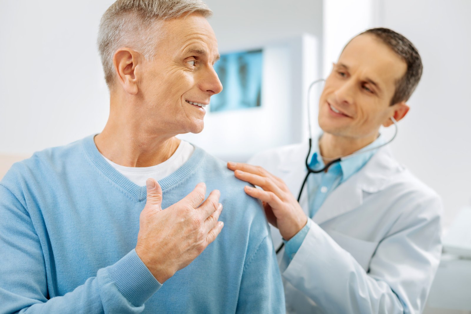 Paciente e médico conversando a respeito da dor do paciente. Eles estão com expressões positivas. Provavelmente o tratamento para lordose está gerando bons resultados.