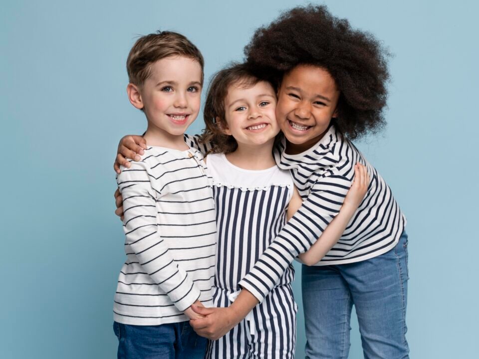 Fotografia de três crianças se abraçando, elas parecem estar feliz pois não possuem macrocefalia.