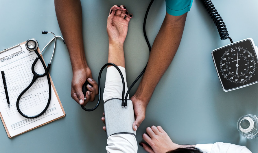 Fotografia de médico consultando um paciente. Ele está medindo a pressão.