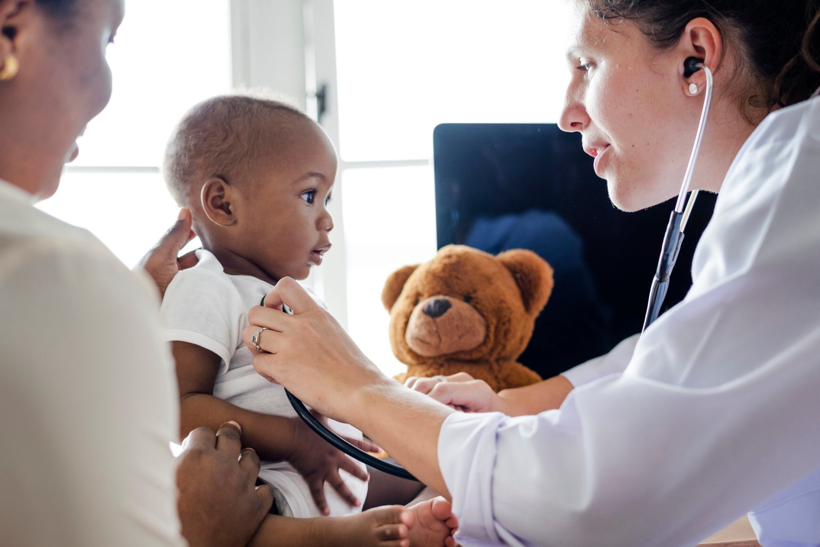 Fotografia de bebê em uma consulta médica. Ele está sendo examinando, a profissional está usando um estetoscópio