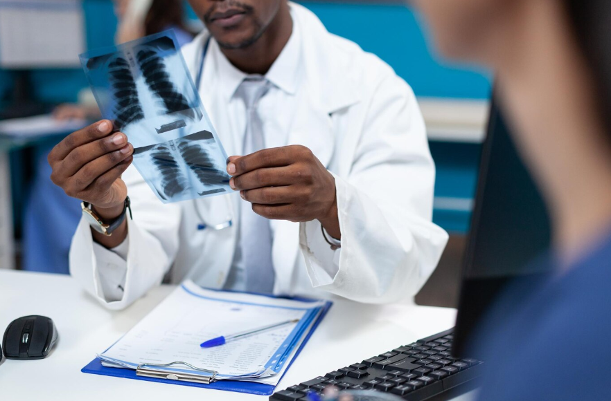 Fotografia de médico analisando exame de imagem de uma coluna em seu consultório