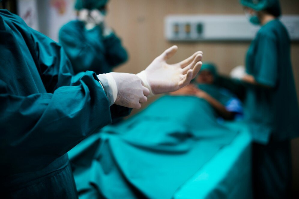 Fotografia de médicos na cirurgia, em que o paciente já está na mesa de cirurgia.